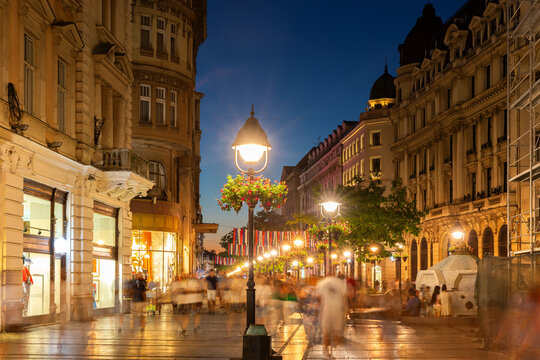 Knez Mihailova Street, Belgrade cultural and commercial hub, captured at night with long exposure with blurred passersby, illuminated shop windows, historic architecture, and vibrant street life - Powered by Adobe