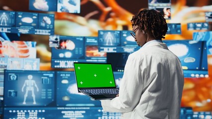 Isolated screen laptop used by scientist to review medical scans. Woman in front of digital health dashboards backdrop analyzing human anatomy with chroma key notebook device, camera A