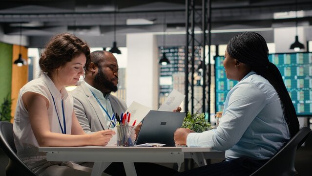 Diverse hiring team and black candidate discuss about qualifications for a job opening within the business organization. Evaluating CV resume information, head hunting concept.