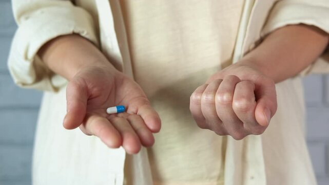 Person choosing between a blue pill and a red pill in a difficult decision. Human hands holding two pills, a blue one and a red one, symbolizing a difficult choice between two options