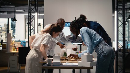 Close up of real estate contractors showing master plan for a housing layout project, using 3D models to present idea of a smart city. Site preparation for urban development vision.