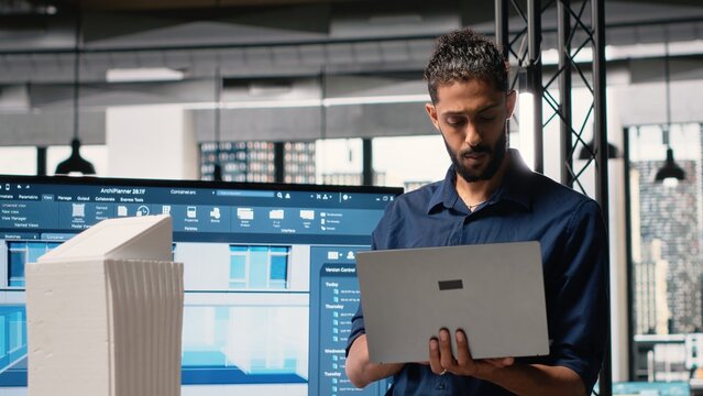 Middle eastern architect reviews blueprints and software for construction master plan, briefing meeting to evaluate measurements and housing layout. Developers with residential project. - Powered by Adobe