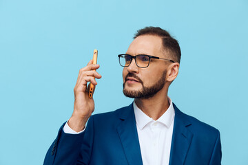 A focused, confident business professional speaks on a phone in a blue suit against a solid blue...