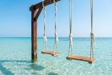 A serene coastal scene featuring two swings suspended above clear, turquoise waters under a bright, cloudless sky. It is perfect place to feel calm and refreshed 