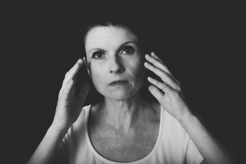 Serious woman touching temples while thinking in studio