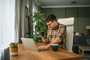 Young man using laptop and smart phone at home office