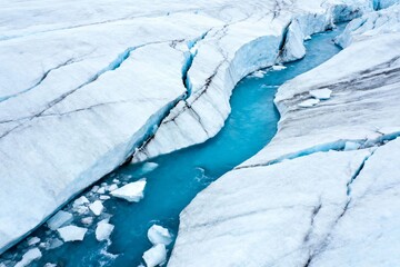 Glacial meltwater flowing through crevasses in a snow-covered ice field