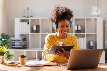 Portrait of teenage African american in afro using laptop computer at home. Teenage boy attending to online school class
