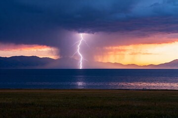 Lightning strikes over a lake during a dramatic sunset with storm clouds and distant mountains
