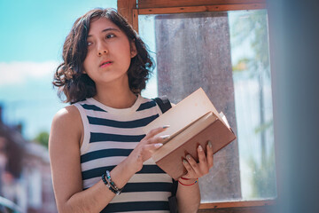 Young woman, take a book from a box of books on the street, she is standing on the sidewalk.