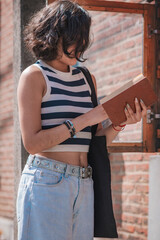 Young woman, take a book from a box of books on the street, she is standing on the sidewalk.
