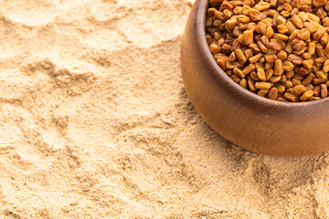 Fenugreek seeds and powder in a wooden bowl - Methi Dana