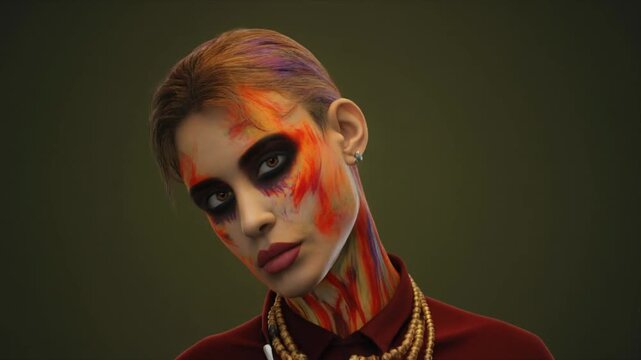 A woman with colorful face paint gazes downward against a dark green background