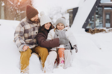 Family embracing winter wonderland sitting together in snow