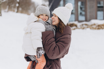 Mother holding happy daughter during winter outdoor fun