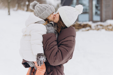 Mother kissing child showing love in winter snow