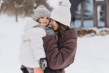 Mother holding daughter smiling outdoors in snow