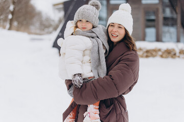Mother holding daughter smiling enjoying winter vacation outdoors