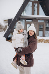 Mother holding daughter enjoying winter snow vacation