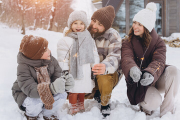 Family enjoying firework sparklers on winter snowy day