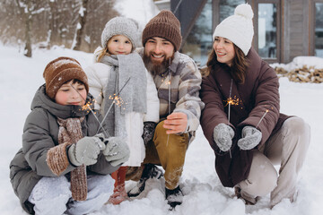 Family enjoying winter holiday with sparklers in snow