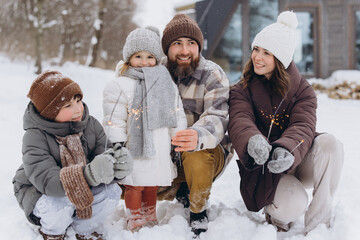 Family enjoying winter vacation holding sparklers in snow