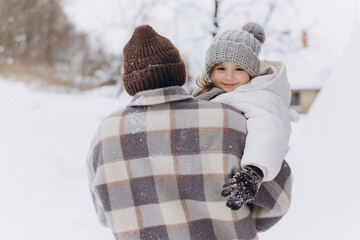 Father carrying daughter during snowy winter playtime