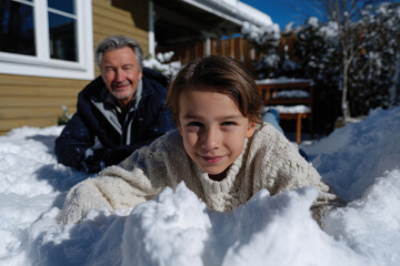 Fototapeta premium A young boy and his grandfather share a playful moment in the snow, highlighting the warmth of family relationships and joyful interactions during a delightful winter day outdoors.