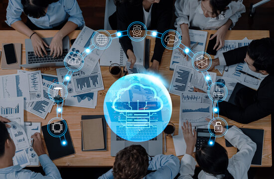 A top view of a diverse group of business professionals engaging in a collaborative meeting, surrounded by laptops and statistical reports, featuring digital cloud icons. Trope - Powered by Adobe