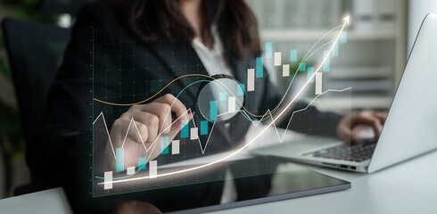 A businesswoman engages with financial data on her laptop, showcasing stock market trends through integrated graphs in a professional office setting. Impute