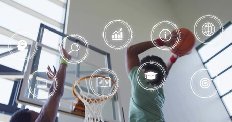 Jumping athlete in green jersey holding orange basketball at rim, defender contesting digital icons
