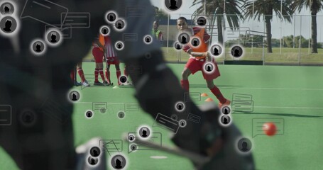 Blocking goalkeeper in dark pads holding stick on turf, with orange ball, red uniforms, chat icons © vectorfusionart