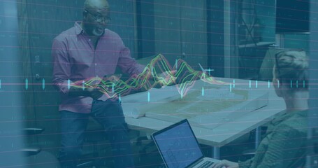 Presenting senior man in shirt gesturing toward model in glass conference room, laptop data overlay