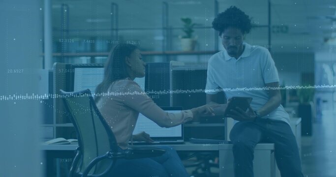 Pointing woman in blouse leaning at laptop in office, man holding tablet viewing data overlay - Powered by Adobe