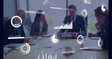 Reading man in suit leading discussion with laptop and papers at meeting table, showing data charts