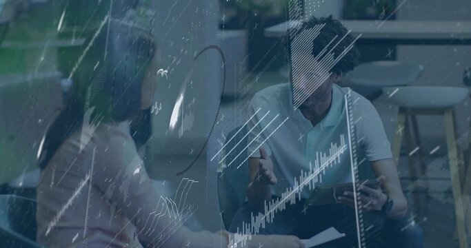 Reviewing tablet and papers, two pros in business casual meeting in office with glass data overlay - Powered by Adobe