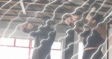 Holding bent elbows fitness partners raising arms in industrial gym with red windows wearing gear