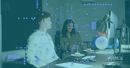 Reaching woman in olive-top and man in hoodie talking over papers in office with HUD, cupcake