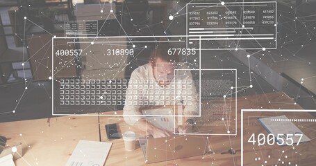Typing woman in light shirt using silver laptop, reviewing documents in office with data and phone