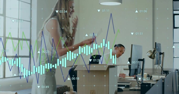 Reviewing overlaid charts, pair wearing sleeveless top and light shirt in office with phone and PCs - Powered by Adobe