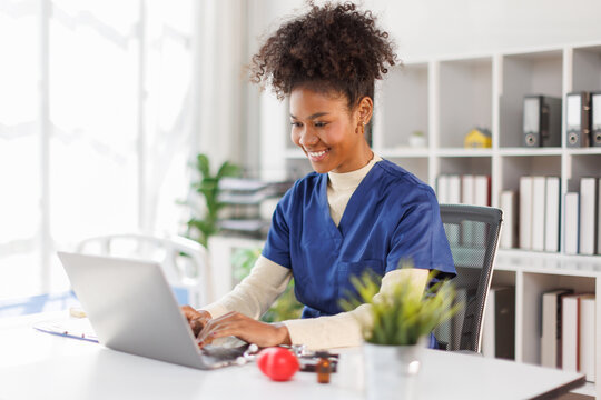 Nurse, A female in afro hair doctor using laptop online, writing notes in medical journal sitting at desk, professional medic physician working on computer at workplace, med student learning, planning