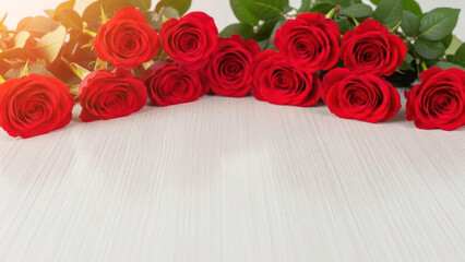 Multiple red roses arranged on a white surface with green leaves.