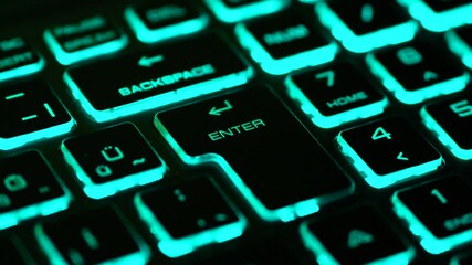 Cyan backlit keyboard with slow zoom toward the Enter key, representing digital focus, data interaction and modern technology interface. - Powered by Adobe