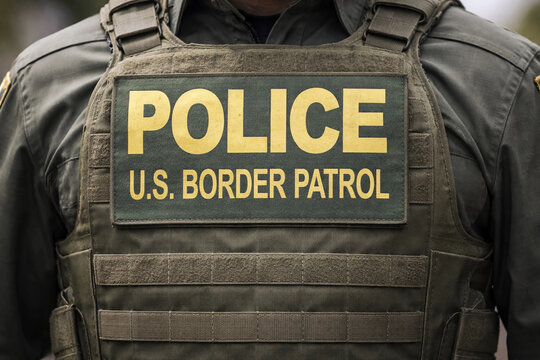 Close-up of a U.S. Border Patrol officer&rsquo;s tactical vest with POLICE patch. Olive green law enforcement gear with MOLLE webbing, photographed outdoors in natural light, symbolizing security and author