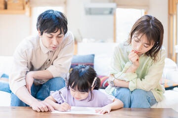 Obraz premium 家でお勉強をする女の子と両親