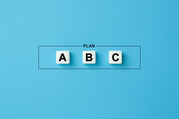 Plan a, b and c on dice cubes on blue background. Choosing a business strategy plan out of three options