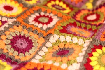 Granny square crocheted blanket with different colors motives, retro vintage craft handmade handiwork crocheting, beautiful plaid photo cozy winter or autumn background wool thing yarn warm bohemian