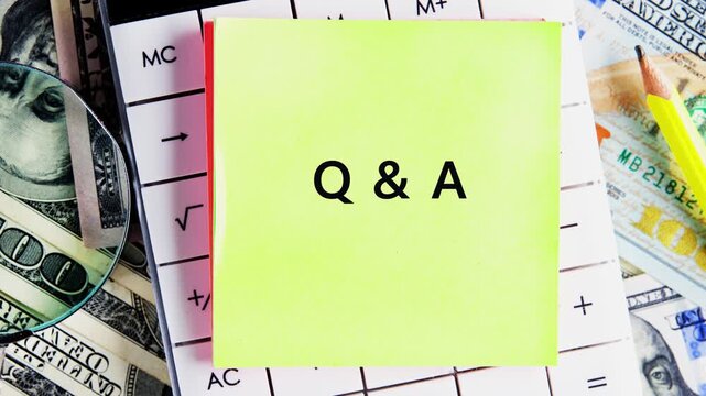 A yellow sticky note displays Q and A. A calculator, United States currency, a pencil, and a magnifier glass rest on a desk. The subject is Finance