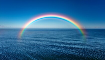 Visible Arc Of Spectral Colors Spans The Deep Blue Ocean Surface Beneath A Clear Sky
