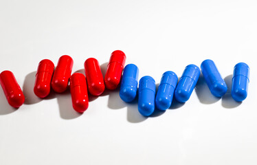 Red and Blue Pill Capsules on White Background with Strong Shadows © Anna Hoychuk